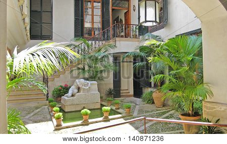 Palma de Majorca Spain - June 25 2008: Typical patio in the historic city of Palma fountain with sculpture and palms