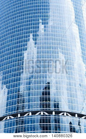 A background with the reflections of sky, clouds and buildings in the windows of a skyscraper.