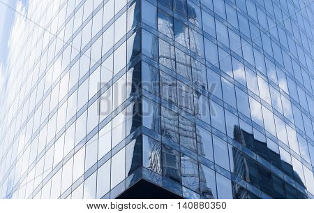 A background with the reflections of sky, clouds and buildings in the windows of a skyscraper.