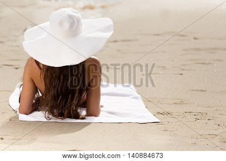Woman in bikini at the beach with a sunhat
