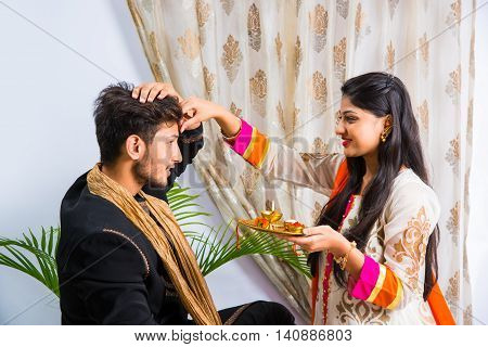 indian sister applying tika on brother's forehead, enjoying and celebrating Raksha Bandhan festival