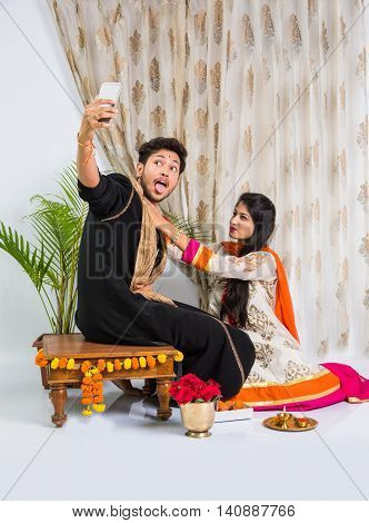 Indian brother taking selfie with sister on Raksha Bandhan festival after tying knot or rakhi