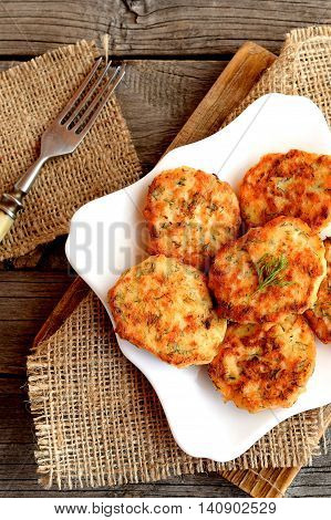 Salmon cutlets with dill on a plate, fork on a wooden table. Delicious salmon patties fried in a pan. Seafood recipe. Top view