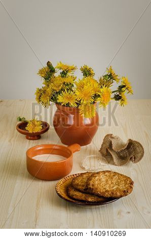 Breakfast with biscuits fermented baked milk a bouquet of dandelions on the wooden desk