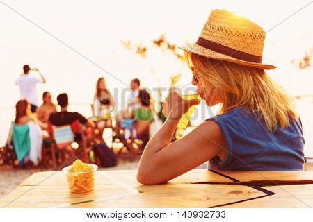 Young woman drinking beer in a beach bar
