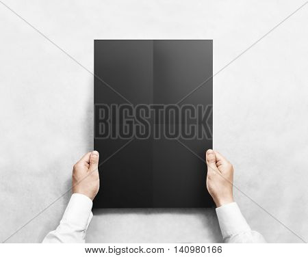 Hand holding black folded blank poster mockup, isolated. Arm in shirt holds clear broadsheet template mock up. Broadside pure print display show. Sticking a3 poster on the wall.