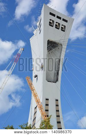 MONTREAL CANADA JULY 30 2016. Men repair the Montreal Olympic Stadium  tower. It's the tallest inclined tower in the world.Tour Olympique stands 175 meters tall and at a 45-degree angle
