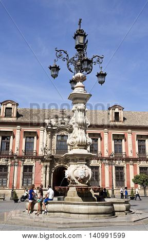 SEVILLE, SPAIN - September 13, 2015: Tourists by the marvellous water fountain and lamp at the Plaza Virgen de los Reyes on September 13, 2015 in Seville, Spain