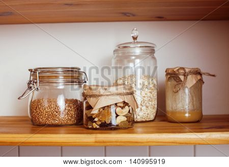 real comfort wooden kitchen with breakfast ingredients close up in glass, honey, oatmeal, milk, muesli