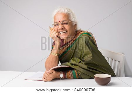 Senior Indian Woman In Traditional Clothes Reading Funny Book