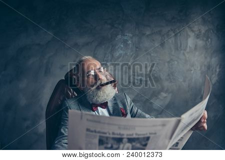 Portrait Of Brutal Attractive Old Man In Tuxedo Holding, Looking At Newspaper, Reading News About Fi