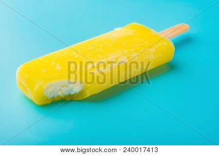 Side View Yellow Popsicle With A Bite On A Blue Background