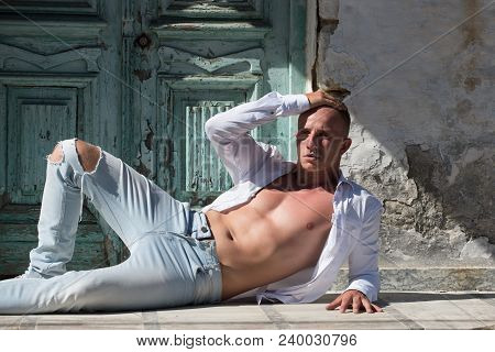 Sexy Macho Man With Bare Chest And Muscular Torso Relax At Wooden Door. Fashion Model In Jeand And S