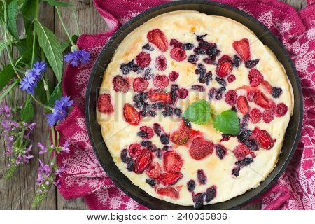 Baked Pancake In Iron Pan With Fresh Strawberries, Rapberries And Honeysuckle