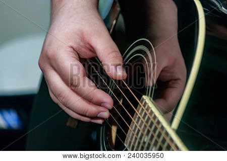 Hand Fingerpicking Strings Of A Black Acoustic Guitar