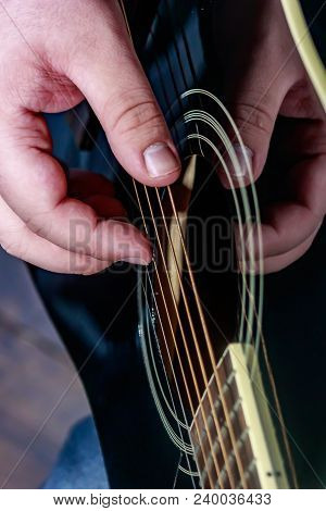 Guitarist Fingerpicking The Strings Of A Black Acoustic Guitar