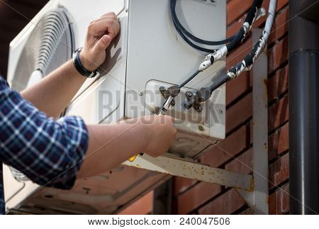 Closeup Photo Of Male Engineer Connecting Pipes To Outdoor Air Conditioner System