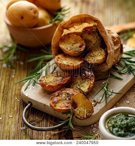 Baked Potatoes. Baked Halves Of Potatoes Seasoned With Rosemary And Sea Salt On A Wooden Rustic Tabl