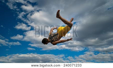 Tricking On Street. Martial Arts. Man Performs Jump With Flip-flop Barefoot. Shooted From Bottom For