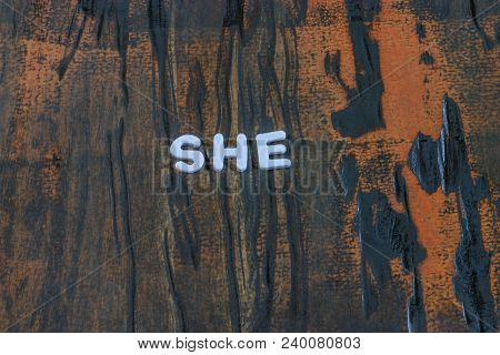 She Written In White Lettering On Dark Weathered Wood