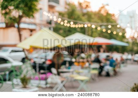 Blurred Background With Group Of Peolple Sitting At The Cafe Veranda Outside.