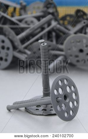A Gray Plastic Dowel Fastening For Thermal Insulation With Round Umbrella Caps Lies On A Gray Foam P