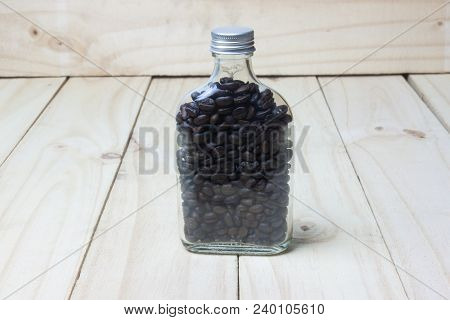 Coffee Beans In Glass Bottle On Wood Background