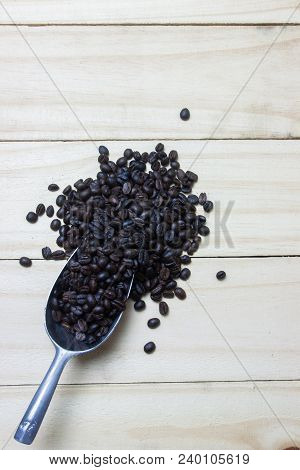 Coffee Beans In Scoop On Wood Background