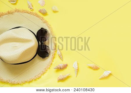 Straw Beach Foman's Hat And Black Sun Glasses With Seashells On Yellow Background. Top View. Flat La
