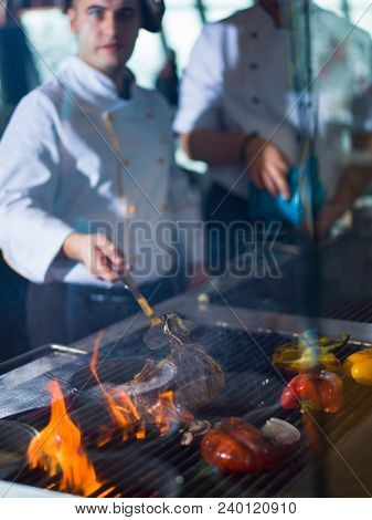 Master chef cooking delicious grilled meat steak with vegetables on a barbecue