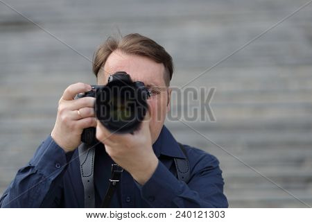 Work Of The Photographer. A Man Looks At The Camera Lens. Journalist.