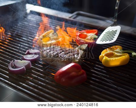 Master chef cooking delicious grilled meat steak with vegetables on a barbecue