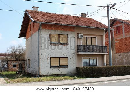 Partially Renovated Suburban House Damaged By Shrapnels During War With Falling Facade, Damaged Wind