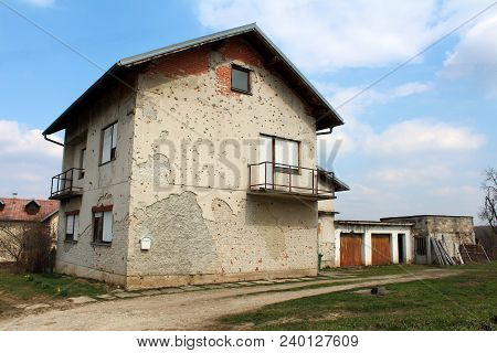 Suburban Family House Heavily Damaged By Shrapnels During War With Dilapidated Facade, Rusted Garage