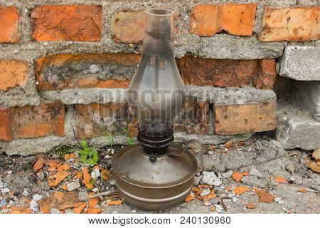 An Old Kerosene Lamp. Old Lamp. Kerosene Lamp. Kerosene Lamp On A Background Of Red Bricks.