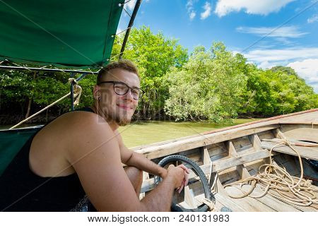Man Travelling On Longtail Boat On Pak Nam River In Krabi In Southern Thailand. Landscape Taken From