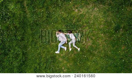 Above View Of Young Couple Holding Hands While Lying On The Grass Like Running. Summer Fun