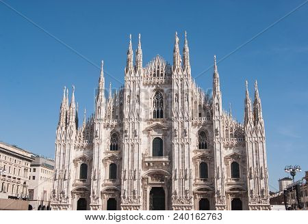 Main Entrance With Spiers And Statues Of The Milan Cathedral And Blue Sky
