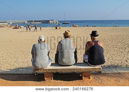 Blanes, Spain - September 11, 2014: Three Older Men Sit On A Bench And Looking At The Sea On Beach O