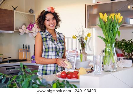 Positive Brunette Female With Curly Hair Makes Salad With Tomatoes And Potato In A Home Kitchen.