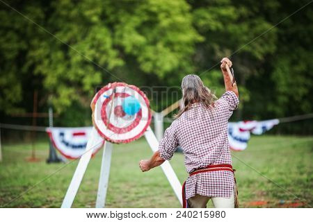 Man throwing an ax at a target , some motion blur, focus on man's left arm