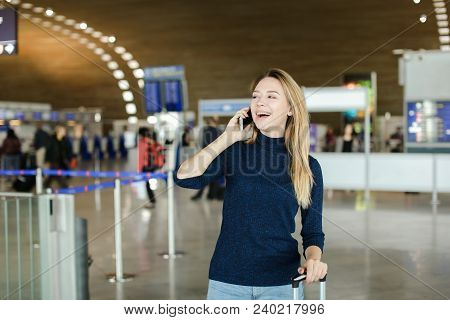 Female Peson Speaking By Smarphone At Airport Hall With Valise. Concept Of Modern Technology And Fly