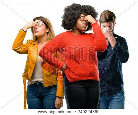 Group of three young men and women with sleepy expression, being overworked and tired, rubbes nose because of weariness