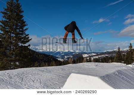 Snowboarder In Action: Jumping In The Mountain Snowpark.
