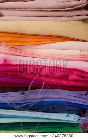 A Pile Of Multicolored Fabrics. Rainbow Fabric Background. Pile Of Bright Folded Fabric