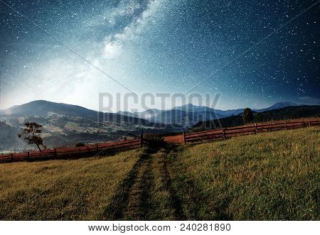 Mountain Summer Landscape. High Grass And Vibrant Night Sky With Stars And Nebula And Galaxy. Deep S
