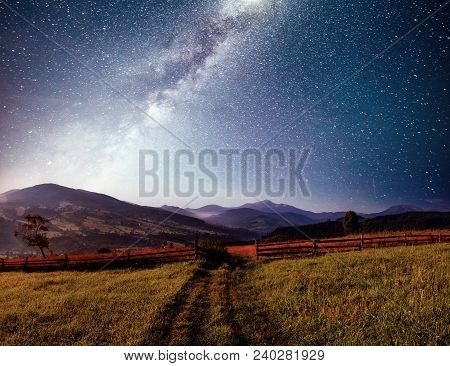 Mountain Summer Landscape. High Grass And Vibrant Night Sky With Stars And Nebula And Galaxy. Deep S