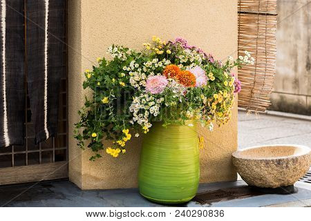 Green Vase With Wild Flowers On A City Street In Kyoto, Japan. Copy Space For Text.