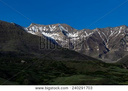 Beautiful Snow-capped Rocky Mountains On A Clear Day With Green Foothills In The Foreground