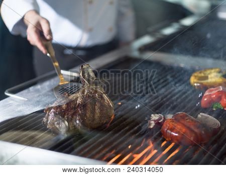 Master chef cooking delicious grilled meat steak with vegetables on a barbecue